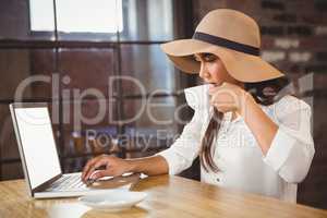 A businesswoman using her laptop while enjoying a coffee