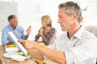 Casual businessman using tablet at lunch