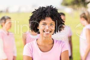 Smiling young woman wearing pink for breast cancer in front of f