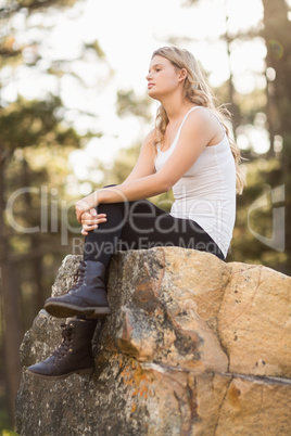 Young jogger sitting on a rock and looking away