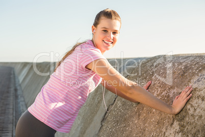 Smiling sporty blonde stretching and listening to music