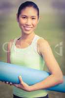 Smiling sporty woman holding exercise mat