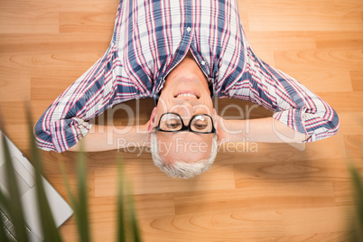 Smiling man lying on floor next to laptop Smiling man lying on floor next to laptop