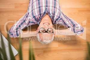 Smiling man lying on floor next to laptop