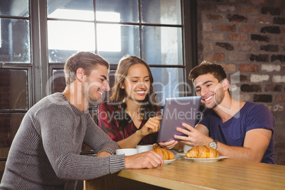 Smiling friends using tablet computer together