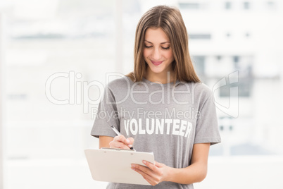 Smiling brunette volunteer writing on clipboard