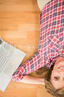 Smiling woman lying on floor next to laptop