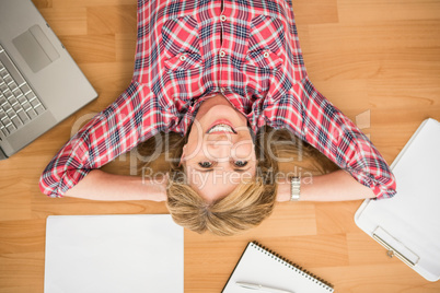 Smiling woman lying on floor surrounded by office items