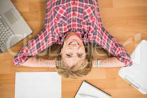 Smiling woman lying on floor surrounded by office items