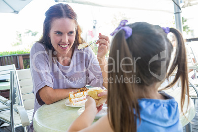 Mother and daughter enjoying cakes at cafe terrace