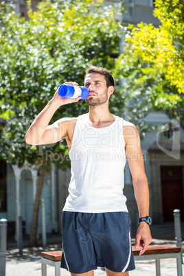 Handsome athlete drinking out of bottle