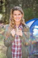 Smiling blonde camper standing in front of tent
