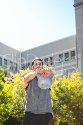 Handsome athlete lifting kettle bell