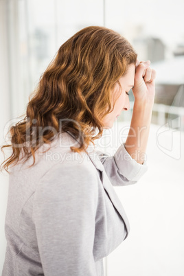 Troubled casual businesswoman leaning against window