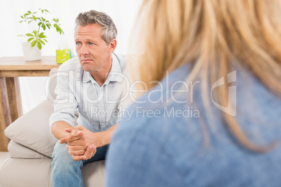 Worried man sitting on couch and talking to therapist