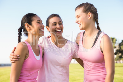 Three laughing women wearing pink for breast cancer