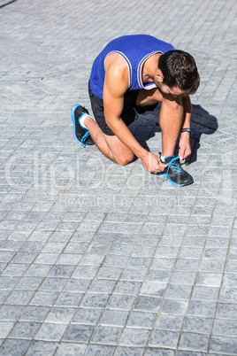 Handsome athlete tying his shoes on a sunny day