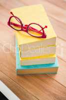 Red reading glasses on stack of books