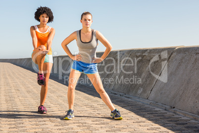 Two young woman stretching together