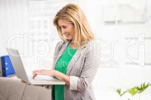 Smiling casual businesswoman working with laptop