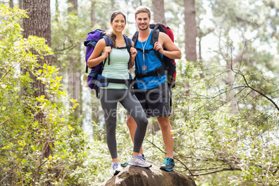 Happy hikers climbing on rock and smiling at camera