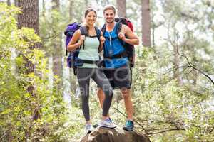 Happy hikers climbing on rock and smiling at camera