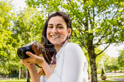 Beautiful brunette taking photo in the park