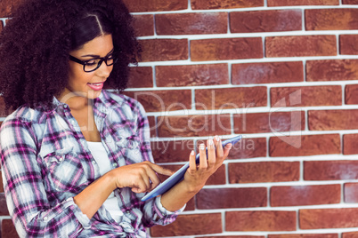 Attractive hipster leaning on wall and using tablet