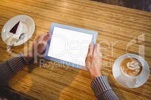 Man with tablet having cappuccino and cake