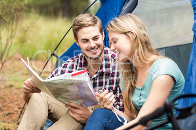 Young pretty hiker couple sitting in a tent looking at map