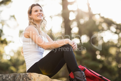 Young happy jogger sitting on rock and looking away