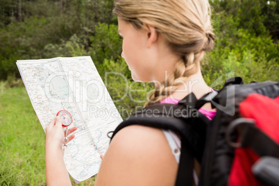 Blonde hiker with compass and reading map