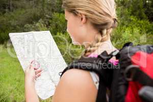 Blonde hiker with compass and reading map