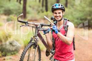 Happy handsome biker holding bike and looking at camera