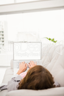 Casual businesswoman relaxing on couch with laptop