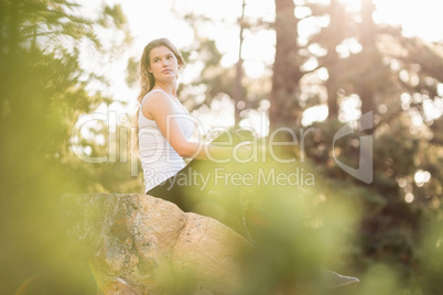 Young jogger sitting on rock and looking away