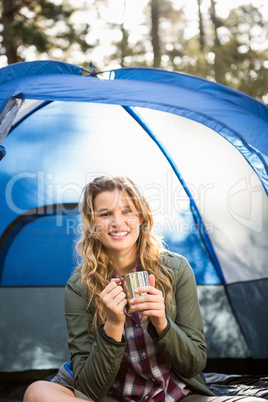 Pretty blonde camper smiling and sitting in tent