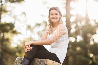 Young happy jogger sitting on rock and looking at camera