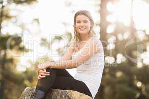 Young happy jogger sitting on rock and looking at camera