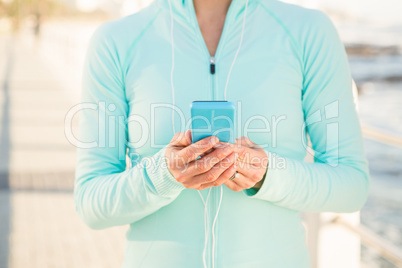 Fit woman listening to music and holding phone