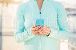 Fit woman listening to music and holding phone