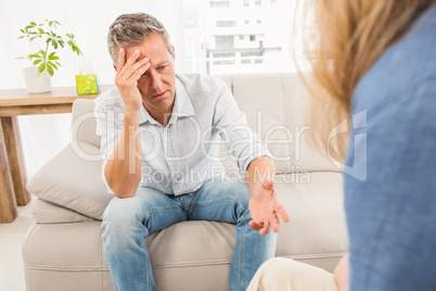 Worried man sitting on couch and talking to therapist