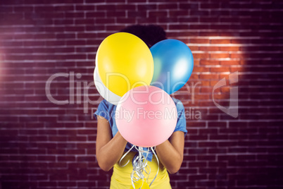 Young woman hiding behind balloons