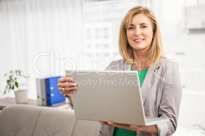 Smiling casual businesswoman with laptop