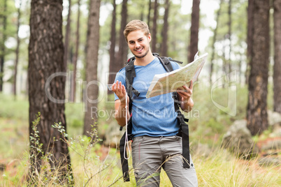 Young handsome hiker using map and compass