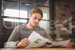 Handsome man having coffee and reading newspaper