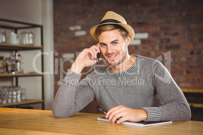 Handsome hipster phoning and holding pen