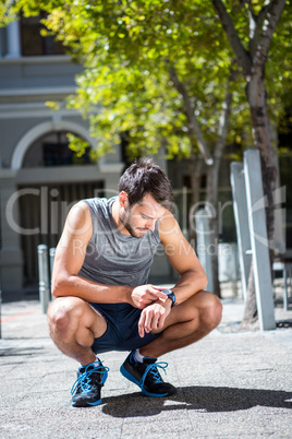 Handsome athlete adjusting his stopwatch