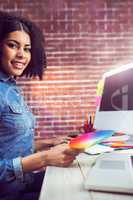 Casual female designer smiling and holding colour chart