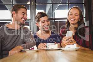 Laughing friends looking at smartphone